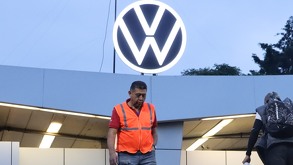Hombre con chaleco fosforescente camina por debajo de un símbolo de Volkswagen en México.