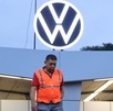 Hombre con chaleco fosforescente camina por debajo de un símbolo de Volkswagen en México.