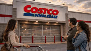 Clientes esperan frente a la entrada cerrada de una tienda Costco con un carrito de compras.