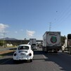 Se observa varios autos parados sobre una carretera; hay tráileres.