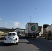 Se observa varios autos parados sobre una carretera; hay tráileres.