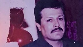 Se observa a un hombre de cabello negro, con bigote color negro y viste una camisa azul.