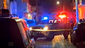 Patrulla de policía estacionada junto a varias personas en la zona de un crimen.