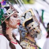 Mujer con pintura sobre el rostro y un penacho frente a la Pirámide de Cholula.
