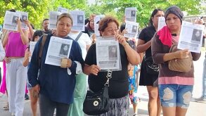 Mujeres caminan con la imagen de una niña desaparecida en Veracruz.