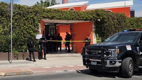 Policías de Jalisco y de Zapopan resguardando una casa color naranja con una patrulla estacionada afuera