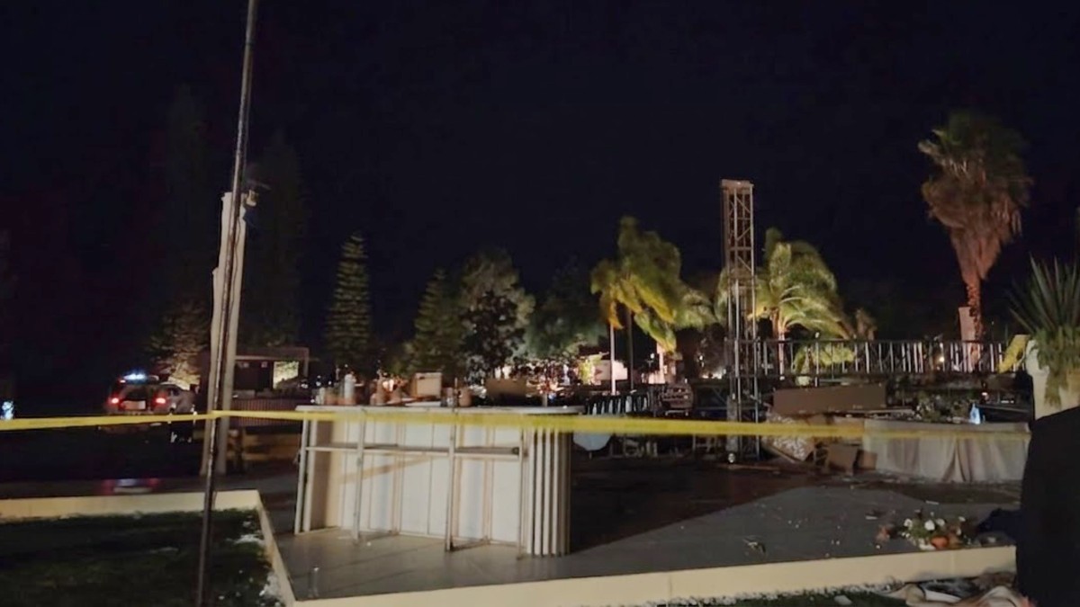 Estructuras metálicas caídas en medio de una terraza acordonada por una cinta policiaca con mesas, sillas y arreglos de boda alrededor