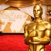 Imagen generada con IA (Sora) de la alfombra roja de los Premios Oscar 2026. Se pueden ver fotógrafos y en primer plano se observa la estatuilla de los premios