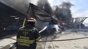 Elemento de Protección Civil y Bomberos de Tlaquepaque arrojando un chorro de agua al fuego dentro de una recicladora
