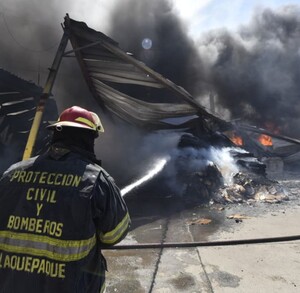 Elemento de Protección Civil y Bomberos de Tlaquepaque arrojando un chorro de agua al fuego dentro de una recicladora
