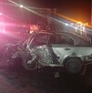 Se observa un carro destruido color gris, es de noche.