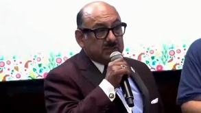 Hombre calvo de lentes hablando frente a un micrófono.