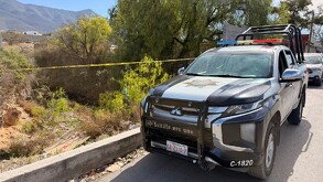 Se observa una patrulla, una cinta amarilla de precaución y un arroyo.