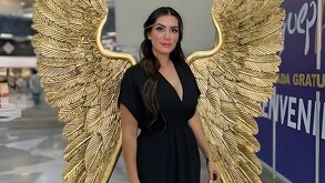 Blanca Estela Álvarez, regidora de Manzanilla de la Paz parada delante de unas alas doradas en un centro de convenciones