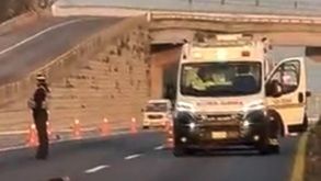 Ambulancia estacionada con una puerta abierta, junto a una oficial de policía.