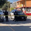Se observa a hombres con uniforme de policías, una patrulla, una cinta amarilla de precaución y al fondo una fachada de tiendas de abarrotes.