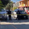 Se observa a hombres con uniforme de policías, una patrulla, una cinta amarilla de precaución y al fondo una fachada de tiendas de abarrotes.