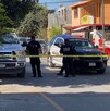 Se observa a hombres con uniforme de policías, una patrulla, una cinta amarilla de precaución y al fondo una fachada de tiendas de abarrotes.