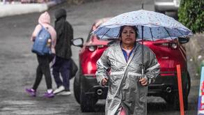 Una ciudadana se protege con una sombrilla de las fuertes lluvias y ráfagas de viento en la Ciudad de México.