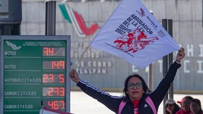 Mujer con una pancarta protesta en una caseta de Oaxaca.