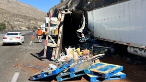 Se observa un tráiler volteado con cajas en el piso, sobre una carretera.