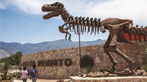T-rex en la entrada del Museo del Desierto con un grupo de personas pasando a su lado.