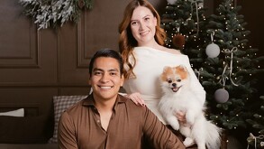 Se observa a una hombre sentado y una mujer, hay un perro color blanco.