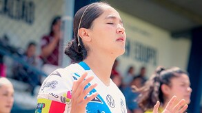 Jugadora de futbol con las manos elevadas al aire.
