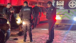Cuatro oficiales de la Policía Municipal de Zapopan resguardando a un hombre que se encuentra en el suelo con una ambulancia de la Cruz Verde en el sitio