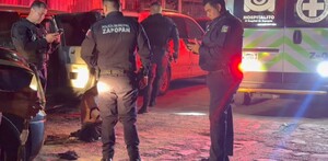 Cuatro oficiales de la Policía Municipal de Zapopan resguardando a un hombre que se encuentra en el suelo con una ambulancia de la Cruz Verde en el sitio