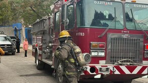 Se observa un camión de bomberos, un hombre vestido con uniforme de bombero.