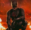 Flyer oficial de la segunda temporada de Daredevil con el superhéroe apoyado sobre su rodilla con un fuego y autos quemados en el fondo