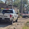 Tres patrullas de la Policía Municipal de Tlaquepaque estacionadas sobre un camino de tierra con cintas policiacas acordonando el área con viviendas alrededor