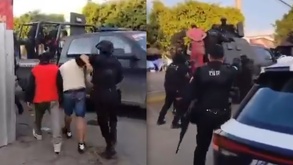 Hombres sometidos siendo llevados a una patrulla de la policía de Puebla.