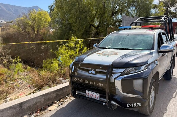 Se observa una patrulla, una cinta amarilla de precaución y un arroyo.