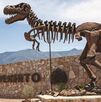 T-rex en la entrada del Museo del Desierto con un grupo de personas pasando a su lado.