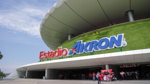 Vista exterior del Estadio Akron con personas vistiendo la jersey de las Chivas del Guadalajara caminando cerca de la entrada