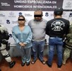 Dos personas detenidas y a sus lados elementos de policía