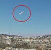 Captura de pantalla del video de un meteorito resaltado con un círculo rojo cruzando el cielo mientras cae en una zona montañosa con árboles en Ohio
