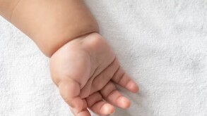 Mano de recién nacido en una toalla en color blanco