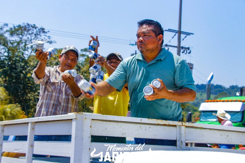Hombres de camisa y sombrero con varias cervezas sobre su mano.