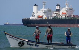 Pescadores pasan junto a un buque petrolero en el golfo de Venezuela