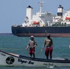 Pescadores pasan junto a un buque petrolero en el golfo de Venezuela