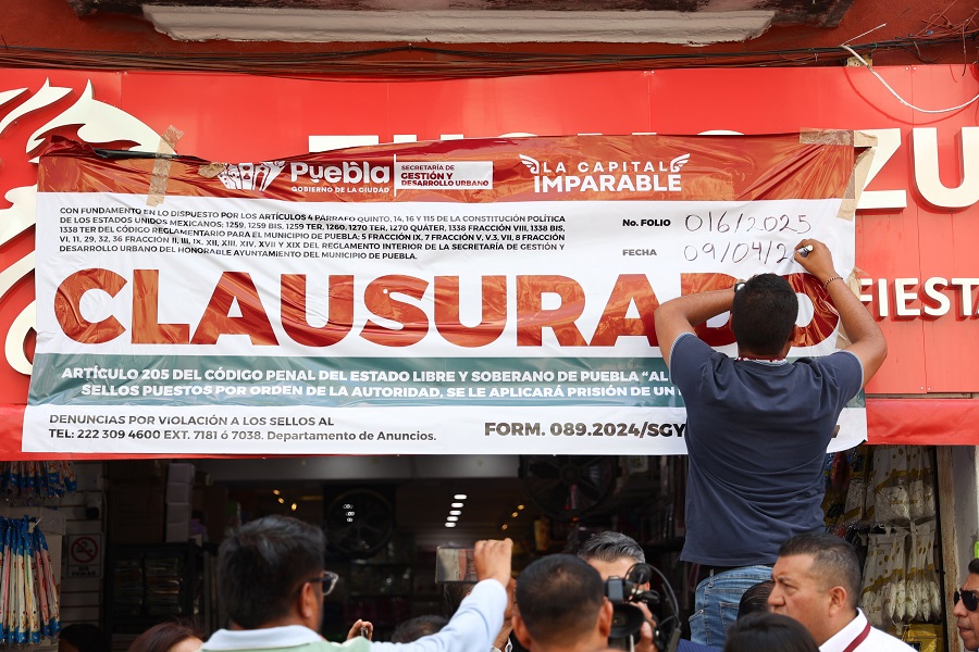 Persona coloca una manta de clausura en un negocio de la ciudad de Puebla.