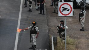 Hombre uniformado de policía muestra una bandera naranja en una autopista.
