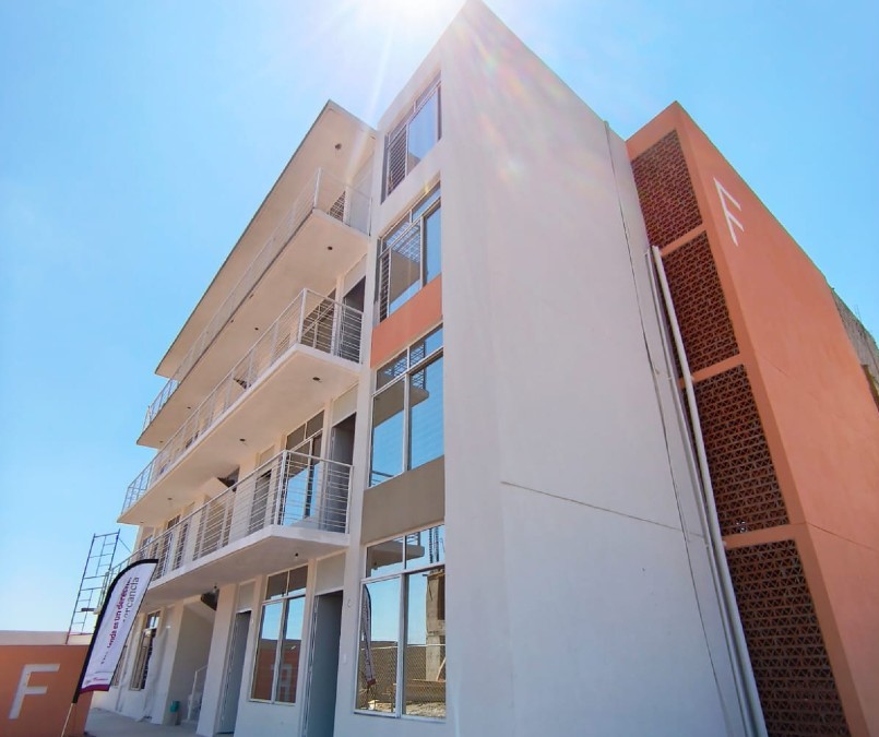 Vista exterior de un edificio de departamentos color naranja con blanco de las Viviendas del Bienestar en El Salto, Jalisco