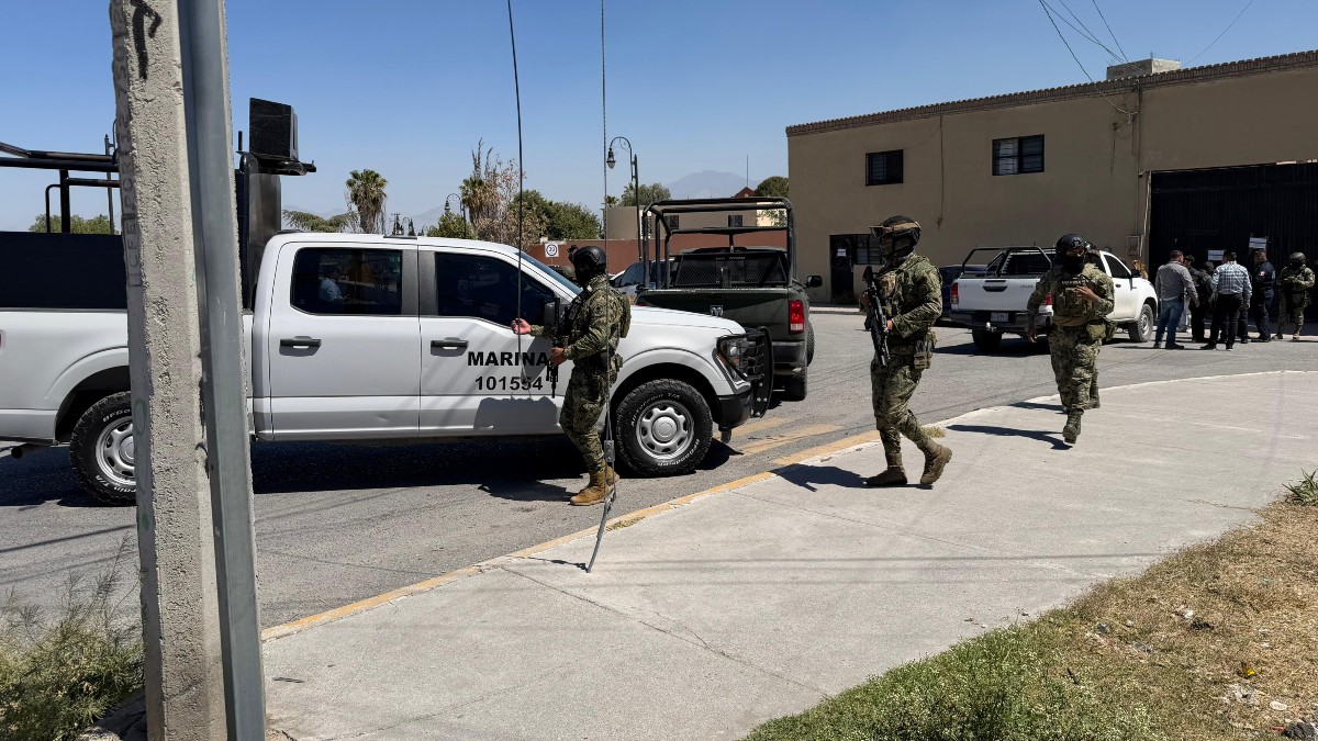 Se observa a varios militares con uniforme verde, en medio de la calle y hay una camioneta blanca.