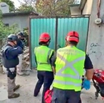 Personal con chaleco fosforescente afuera de una vivienda.