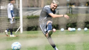 Futbolista de cabello rubio golpeando una pelota con la pierna.