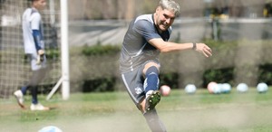 Futbolista de cabello rubio golpeando una pelota con la pierna.